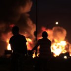 Two boys watch the flames rising from the Amuay refinery on Sunday. (AP Photo/Ariana Cubillos/PA)