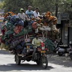 Indian workers sit on a pile of cloth material being transported at Jetpur near Rajkot, about 300kms southwest of Ahmadabad, India. (AP Photo/Ajit Solanki)