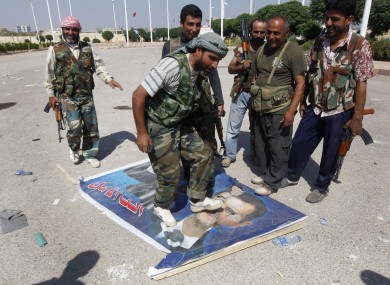 A Free Syrian Army fighter from the Al-Faruk brigade, center, steps on a portrait of Syrian President Bashar Assad, at the Tal Abyad, a Turkish-Syrian border crossing captured by the rebels earlier in the week