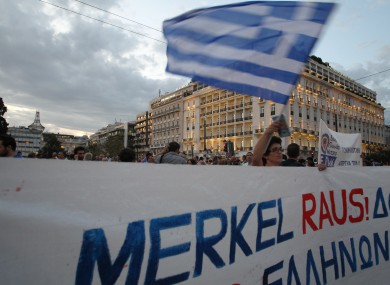A protestor waves a Greek flag in Athens on Monday, Oct. 8, 2012 during an union anti-austerity rally a day before the visit by German Chancellor Angela Merkel.