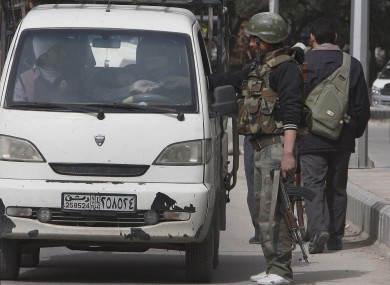 A Syrian government security forces soldier, stands at a checkpoint as he checks the identity cards of Syrian citizens in Damascus, Syria.