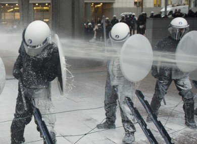 Police officers are sprayed with milk by the European milk farmers during the demonstration in front of the European Parliament building in Brussels yesterday.
