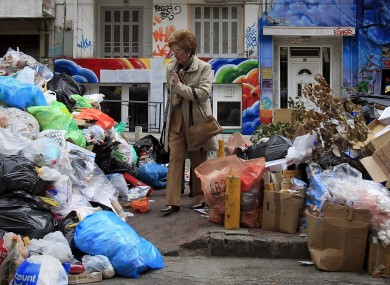 A woman passes by piles of garbage amassed during succesive strikes by municipal workers in the Greek city of Thessaloniki.