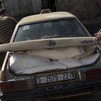 Palestinians jump into a car after collecting bags of flour at a UN distribution center in Shati refugee camp, Gaza City.
(AP Photo/Bernat Armangue)