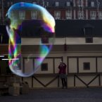 A woman takes a snapshot of a bubble in Madrid's Plaza Mayor. AP Photo/Daniel Ochoa de Olza)