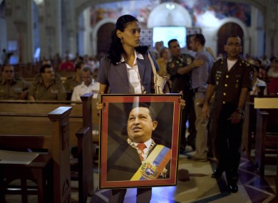 A woman carries an image of Hugo Chavez before a mass in support of him in Cuba